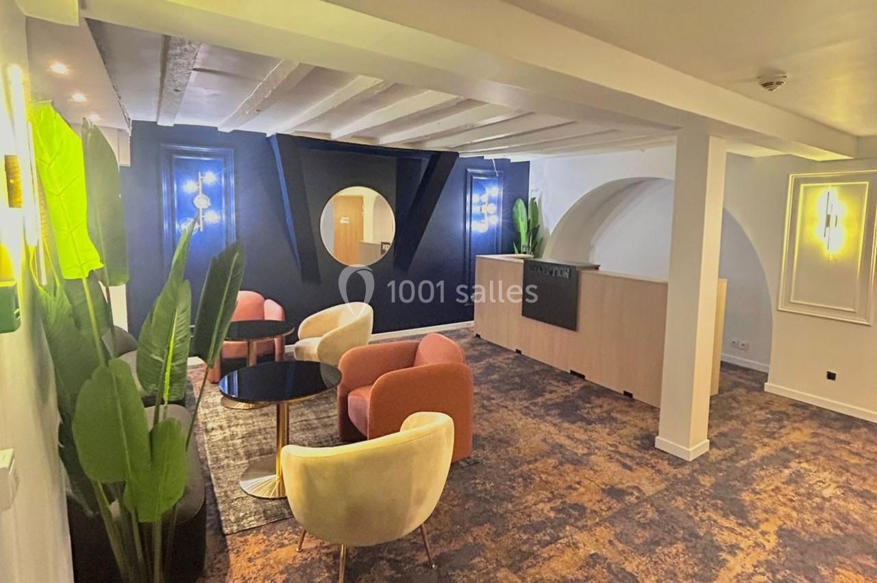 Espace lounge moderne avec fauteuils colorés, plantes décoratives et éclairage chaleureux dans un intérieur lumineux.