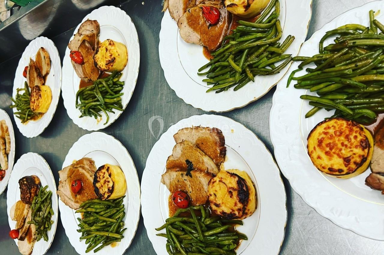 Assiettes garnies de viande rôtie, haricots verts, pommes de terre gratinées et tomates cerises grillées.