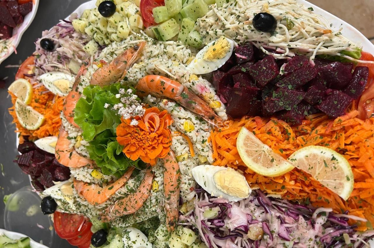 Plateau coloré de crudités variées avec crevettes, œufs durs, légumes frais, betteraves et décoration florale.