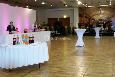 Miniature Location salle Reims (Marne) - Champagne Castelnau - Caveau et Celliers de Réceptions #13 Salle de réception décorée avec des tables rondes, nappes blanches, rubans rouges et tonneaux en arrière-plan.