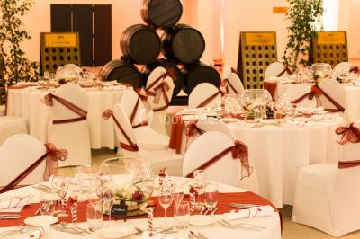 Miniature Location salle Reims (Marne) - Champagne Castelnau - Caveau et Celliers de Réceptions #15 Salle de réception décorée avec des tables rondes, nappes blanches, rubans rouges et tonneaux en arrière-plan.