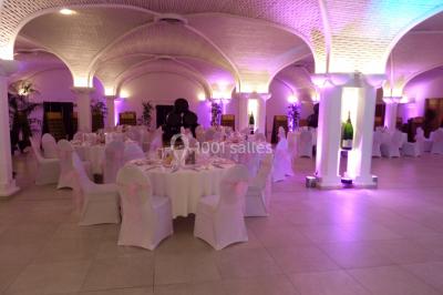 Miniature Location salle Reims (Marne) - Champagne Castelnau - Caveau et Celliers de Réceptions #10 Salle de réception décorée avec des tables rondes, nappes blanches, rubans rouges et tonneaux en arrière-plan.