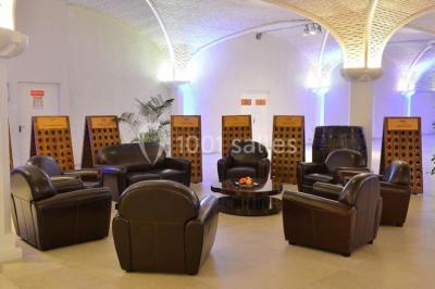 Miniature Location salle Reims (Marne) - Champagne Castelnau - Caveau et Celliers de Réceptions #14 Salle de réception décorée avec des tables rondes, nappes blanches, rubans rouges et tonneaux en arrière-plan.