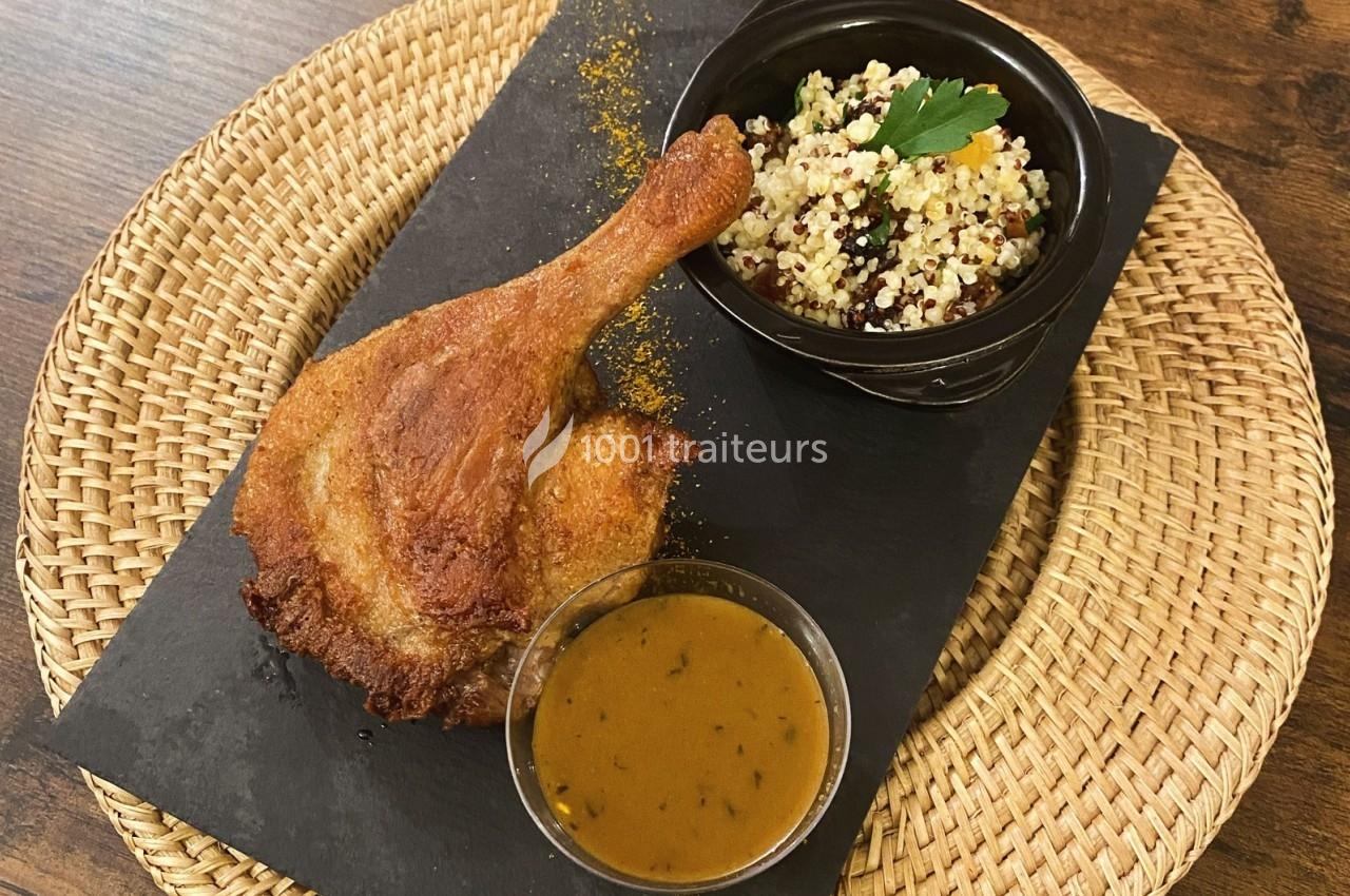Cuisse de poulet rôtie servie avec une sauce, du quinoa aux herbes et légumes, présentée sur une ardoise noire.