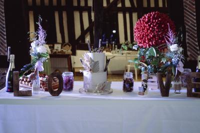 Deux hommes cuisinent des aliments sur un grand barbecue en plein air, éclairé par les flammes, à la tombée de la nuit.