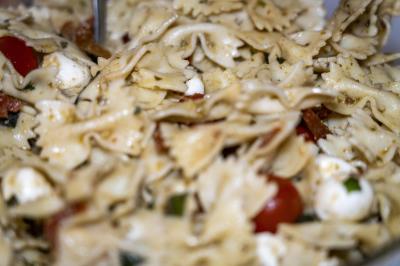 Deux hommes cuisinent des aliments sur un grand barbecue en plein air, éclairé par les flammes, à la tombée de la nuit.