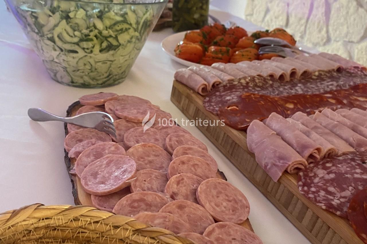 Plateaux de charcuterie variée avec salami, jambon et saucisson, accompagnés de salades de concombre et tomates.
