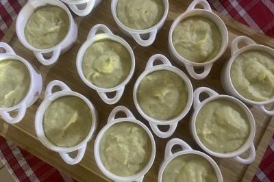 Deux hommes cuisinent des aliments sur un grand barbecue en plein air, éclairé par les flammes, à la tombée de la nuit.