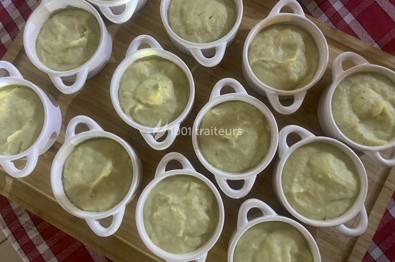 Petites cocottes blanches remplies de purée disposées sur une planche en bois, posée sur une nappe à carreaux rouges.