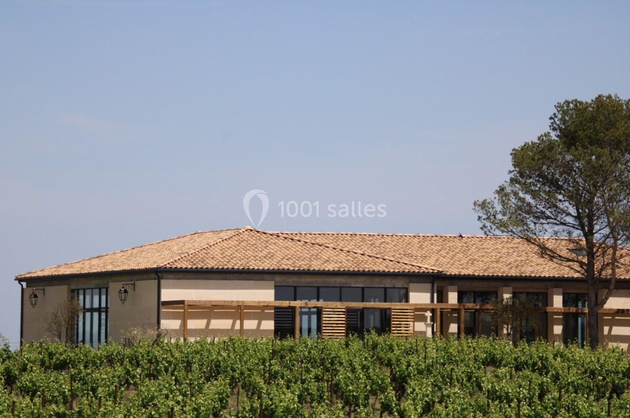 Bâtiment à toit en tuiles entouré de vignes sous un ciel dégagé.