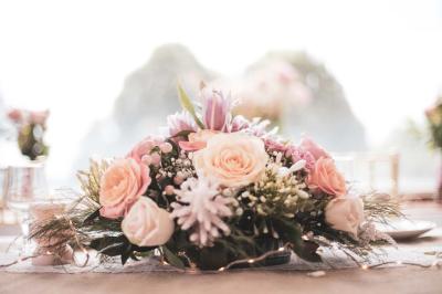 Salle lumineuse décorée pour un événement, avec des tables dressées, des chaises dorées et des fleurs en centre de table.