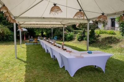 Salle lumineuse décorée pour un événement, avec des tables dressées, des chaises dorées et des fleurs en centre de table.