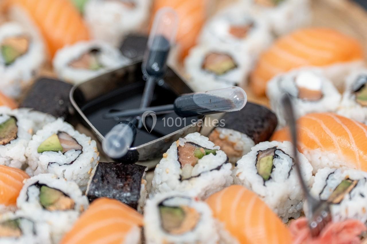 Plateau de sushis variés avec makis, nigiris et pipettes de sauce soja au centre.