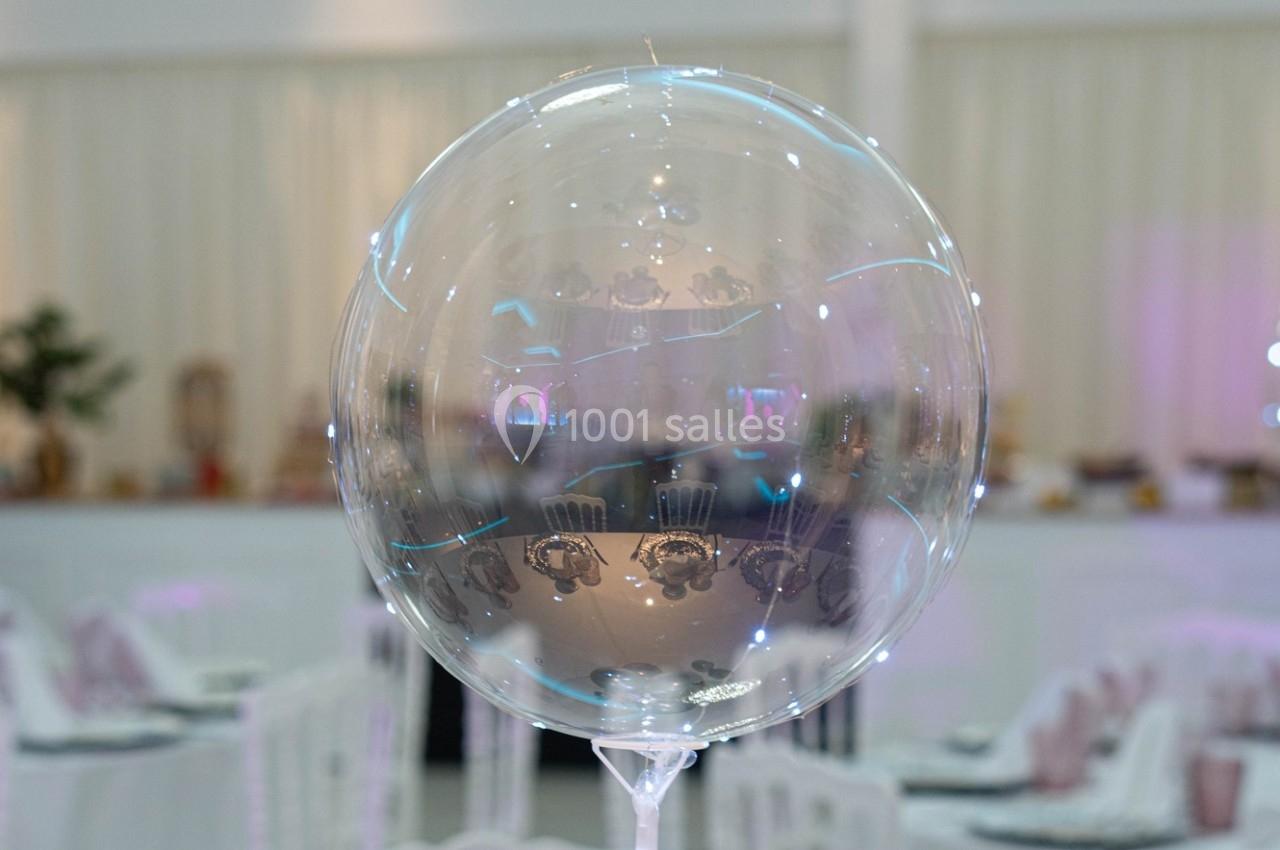 Ballon transparent décoratif avec des motifs et des lumières LED, placé dans une salle de réception lumineuse.
