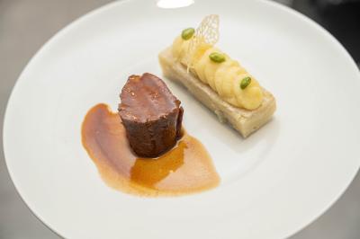 Plat gastronomique composé d'un morceau de viande nappé de sauce et d'un accompagnement de pommes de terre dressées…