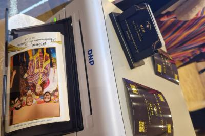 Quatre bandes de photos imprimées montrant des personnes souriantes dans un photomaton, posées sur une surface grise.