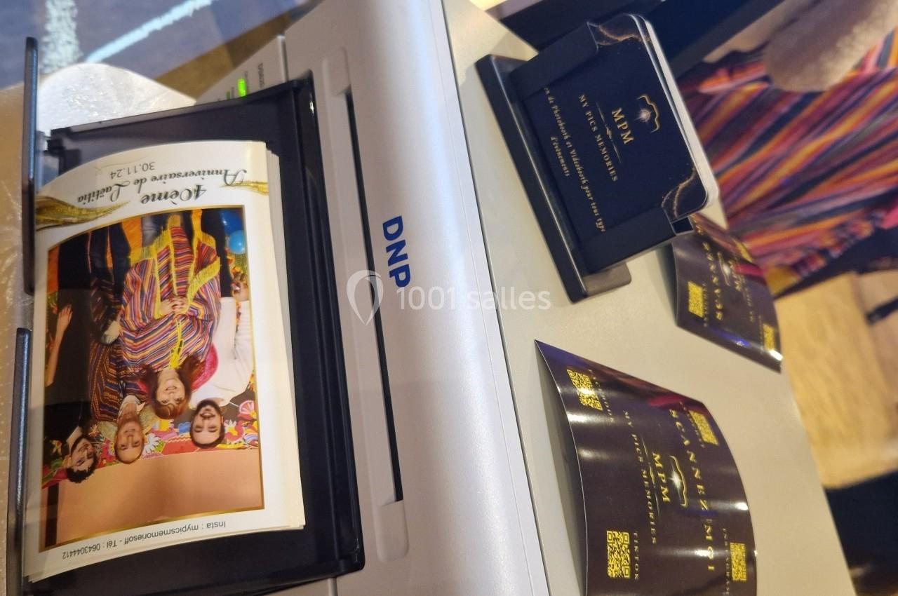 Impression d'une photo couleur sur une imprimante DNP, entourée de cartes de visite et d'éléments promotionnels.