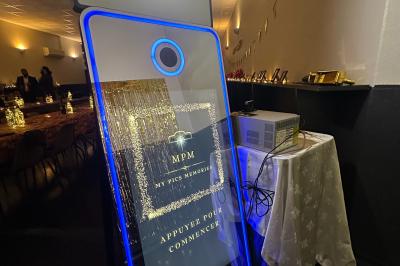 Miniature Photobooth Miroir Prestige Accessoires de fête colorés sur une table en bois, incluant lunettes, moustaches, micro et pistolets dorés.