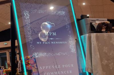 Miniature Photobooth Miroir Prestige Accessoires de fête colorés sur une table en bois, incluant lunettes, moustaches, micro et pistolets dorés.