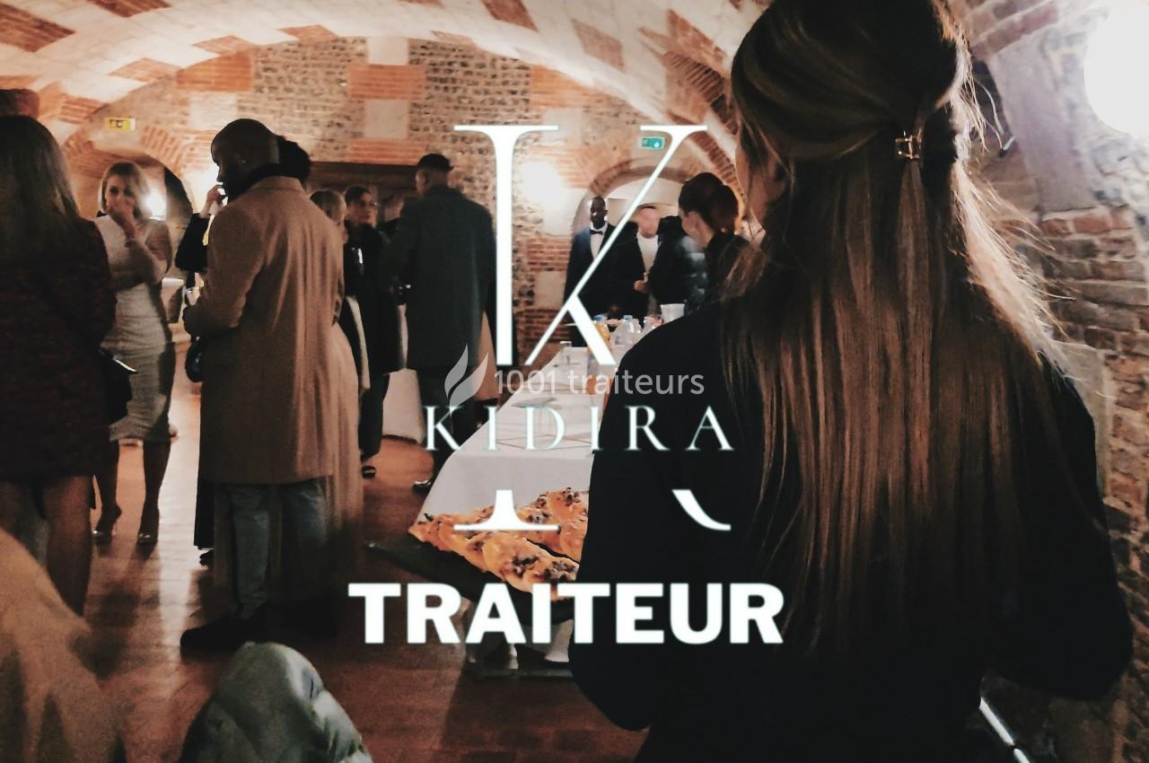 Des convives discutent dans une salle voûtée en briques, avec un buffet visible au premier plan.