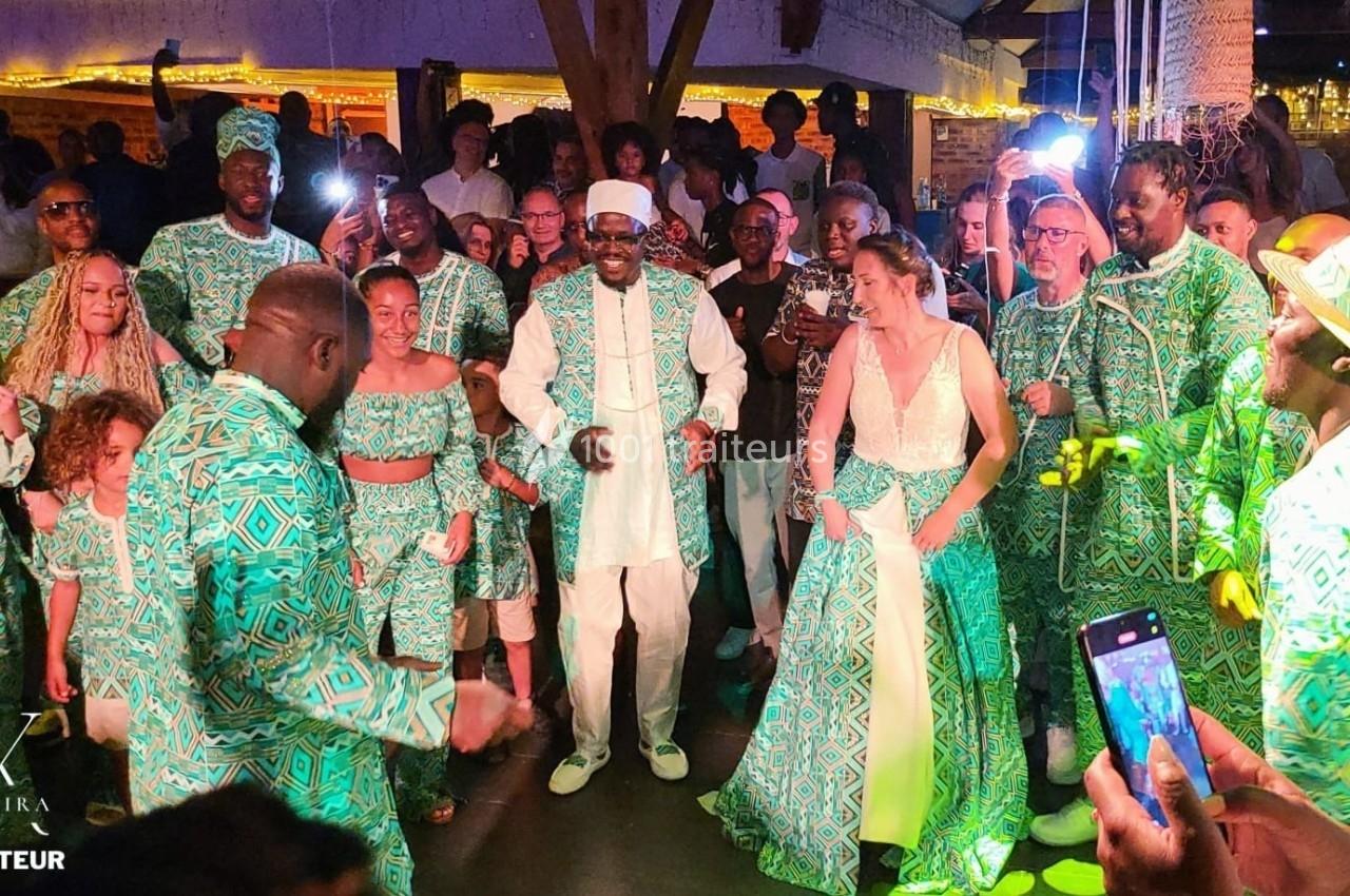 Un groupe de personnes danse lors d'une fête, habillé en tenues traditionnelles vertes et blanches.