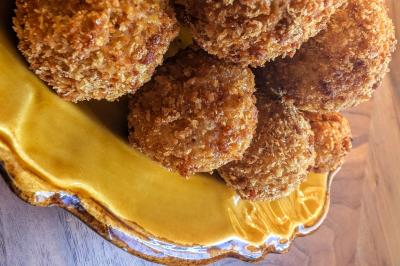 Une personne coupe un oignon sur une planche en bois, entourée de légumes frais et d'herbes aromatiques.
