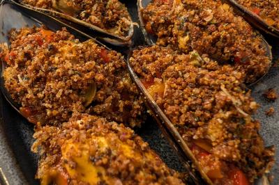 Une personne coupe un oignon sur une planche en bois, entourée de légumes frais et d'herbes aromatiques.