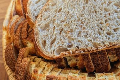 Une personne coupe un oignon sur une planche en bois, entourée de légumes frais et d'herbes aromatiques.