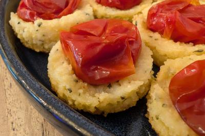Une personne coupe un oignon sur une planche en bois, entourée de légumes frais et d'herbes aromatiques.