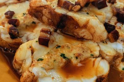 Une personne coupe un oignon sur une planche en bois, entourée de légumes frais et d'herbes aromatiques.