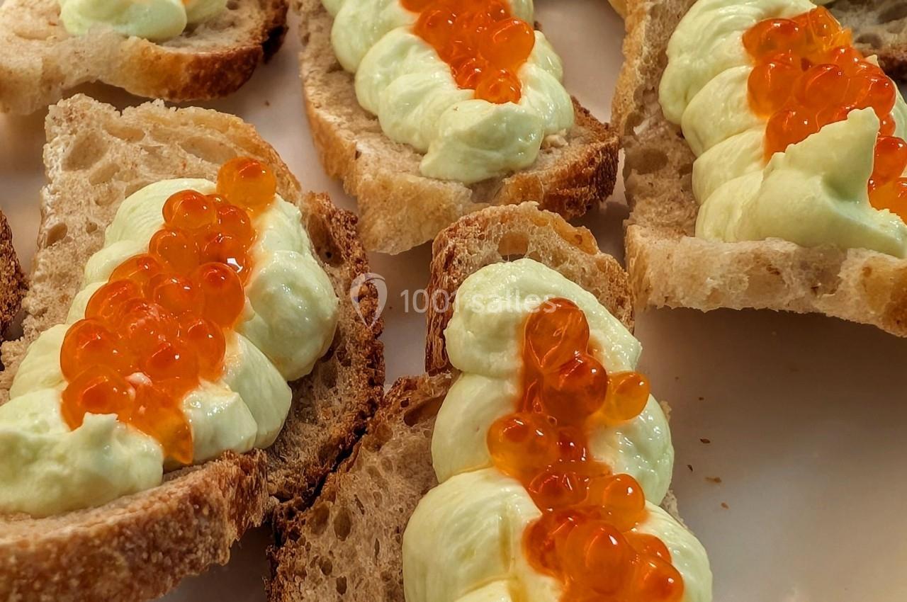 Tranches de pain garnies de mousse verte et de perles orange, probablement des œufs de poisson.