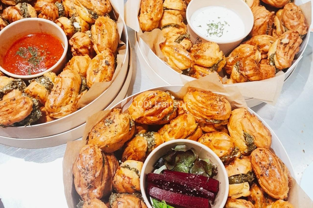 Plateaux garnis de feuilletés dorés, accompagnés de sauces et de betteraves, présentés sur du papier kraft.