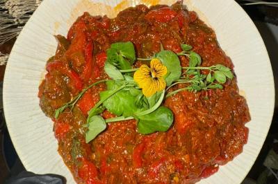 Tranches d'orange garnies de groseilles, pétales de fleurs, amandes effilées et feuilles de menthe dans une assiette.