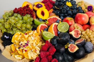 Tranches d'orange garnies de groseilles, pétales de fleurs, amandes effilées et feuilles de menthe dans une assiette.