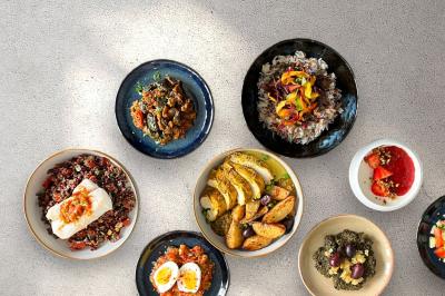 Tranches d'orange garnies de groseilles, pétales de fleurs, amandes effilées et feuilles de menthe dans une assiette.