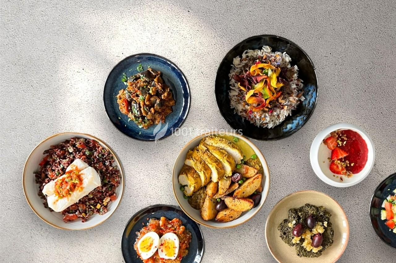 Assortiment de plats colorés comprenant légumes, céréales, poisson, pommes de terre et desserts sur une table grise.