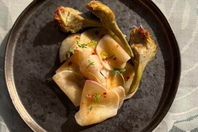 Tranches d'orange garnies de groseilles, pétales de fleurs, amandes effilées et feuilles de menthe dans une assiette.