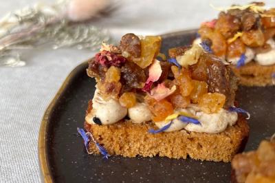 Tranches d'orange garnies de groseilles, pétales de fleurs, amandes effilées et feuilles de menthe dans une assiette.