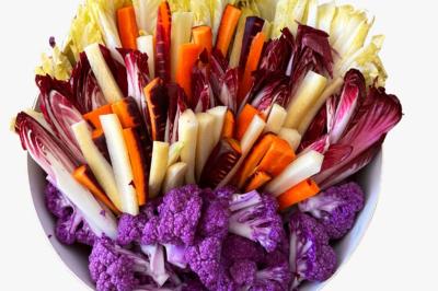 Tranches d'orange garnies de groseilles, pétales de fleurs, amandes effilées et feuilles de menthe dans une assiette.