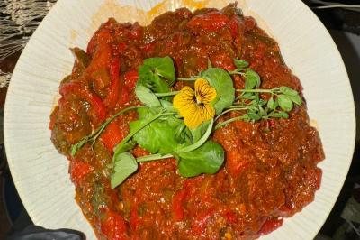 Tranches d'orange garnies de groseilles, pétales de fleurs, amandes effilées et feuilles de menthe dans une assiette.