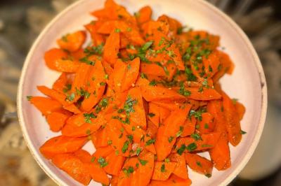 Tranches d'orange garnies de groseilles, pétales de fleurs, amandes effilées et feuilles de menthe dans une assiette.