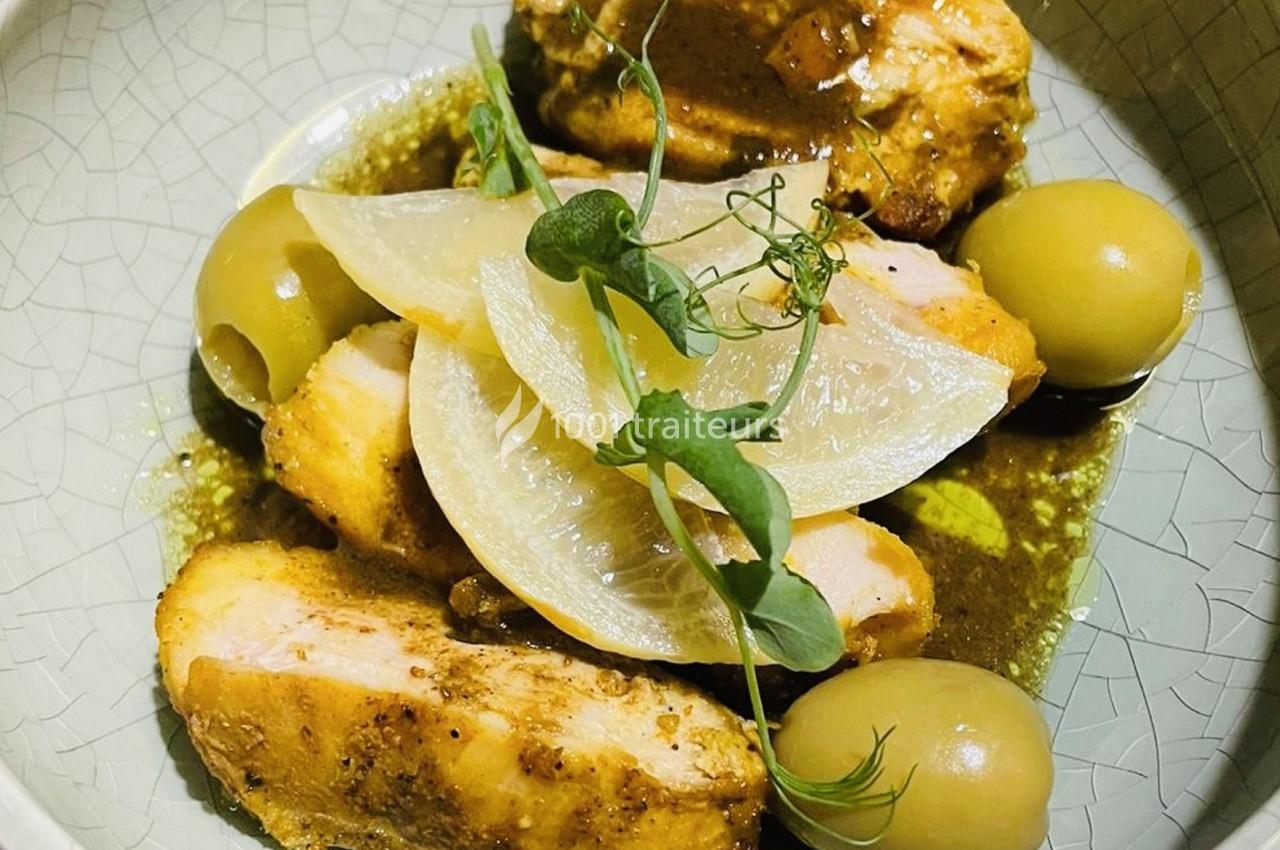 Poulet rôti en tranches avec olives vertes, rondelles d'oignon et herbes fraîches, servi dans une assiette claire.