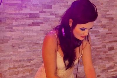 Miniature DJ Saint-Julien-de-Concelles (Loire-Atlantique) - JennyJazz #12 Femme concentrée, portant une robe claire, devant un mur en pierre texturée sous un éclairage violet.