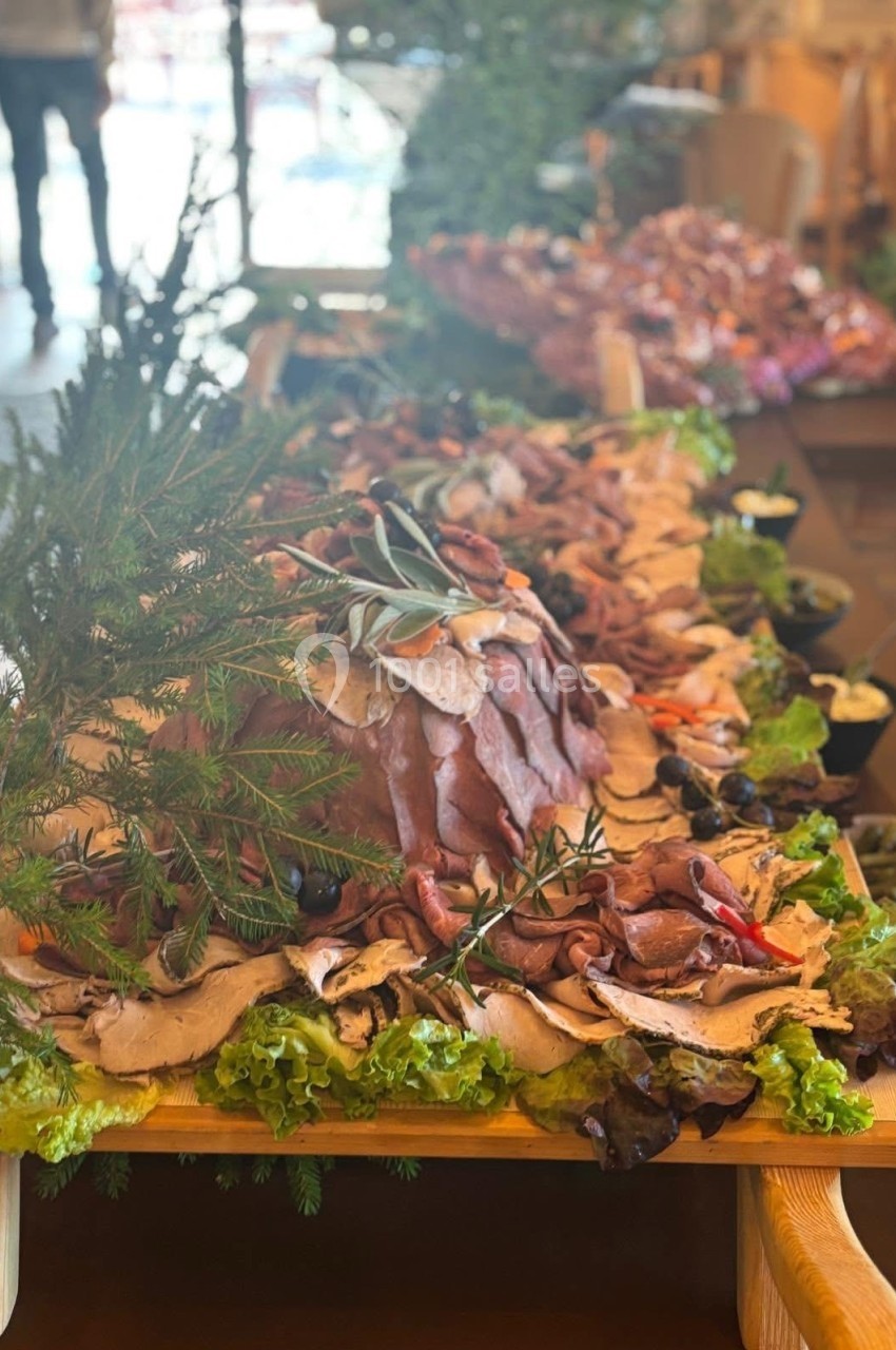 Plateau de charcuterie et viandes froides décoré de légumes, herbes fraîches et feuilles de salade.