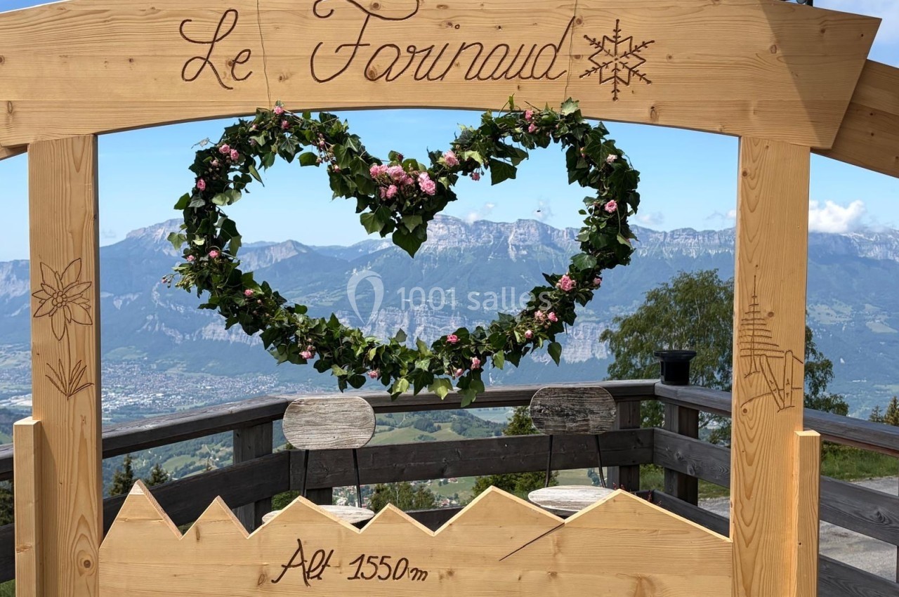 Arche en bois décorée d'une couronne en forme de cœur avec vue sur des montagnes et une vallée en arrière-plan.
