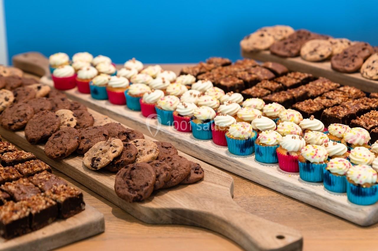 Plateaux en bois garnis de brownies, cookies et mini cupcakes colorés sur une table en bois.