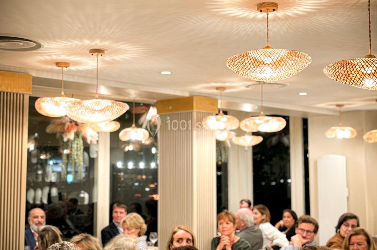Des personnes assises dans un restaurant éclairé, écoutant attentivement une présentation ou un discours.