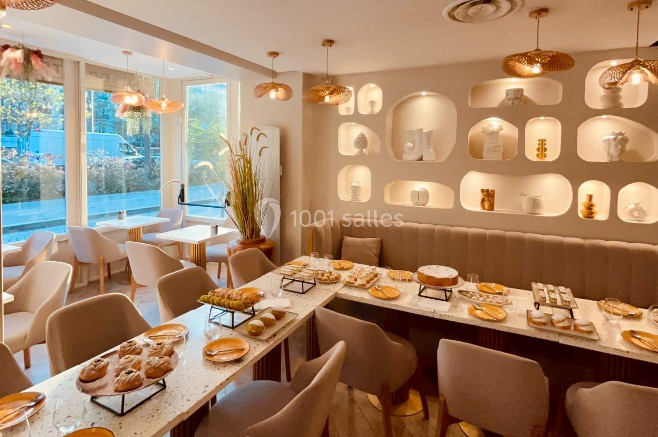 Salle lumineuse avec tables dressées pour un buffet, décor moderne et étagères murales ornées d'objets décoratifs.