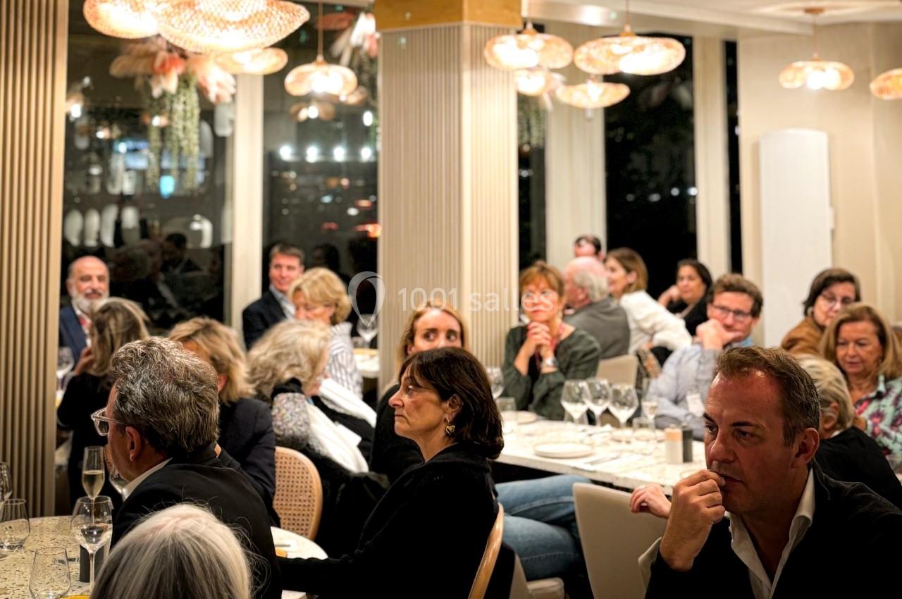 Groupe de personnes assises dans un restaurant, attentives à une présentation ou une discussion.