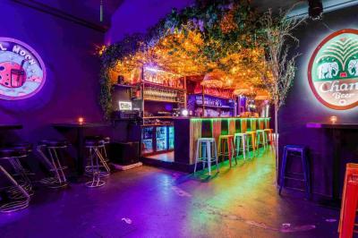 Miniature Location salle Lille (Nord) - Fullmoon #3 Façade d'un bar avec une décoration végétale, des néons roses et des tabourets noirs sur le trottoir.